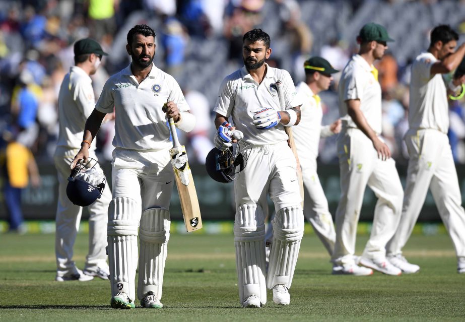 India's Cheteshwar Pujara (left) and Virat Kohli leave the field after play on day one of the third cricket test between India and Australia in Melbourne, Australia on Wednesday.