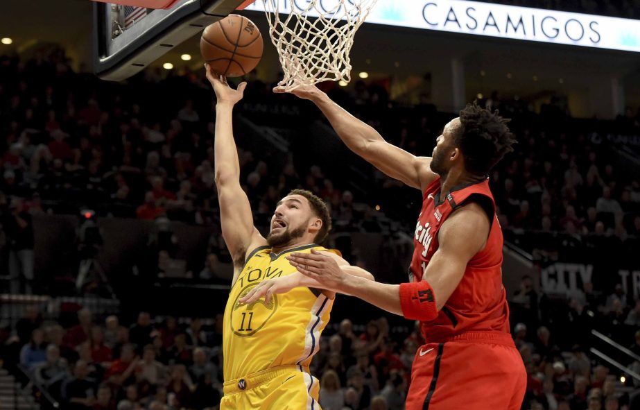 Golden State Warriors guard Klay Thompson (left) drives to the basket on Portland Trail Blazers guard Evan Turner (right) during the first half of an NBA basketball game in Portland, Ore. on Saturday.