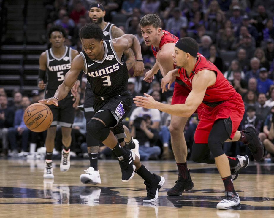 Sacramento Kings guard Yogi Ferrell (3) races past Portland Trail Blazers' Meyers Leonard center and Seth Curry (right) during the first half of an NBA basketball game in Sacramento, Calif on Tuesday.