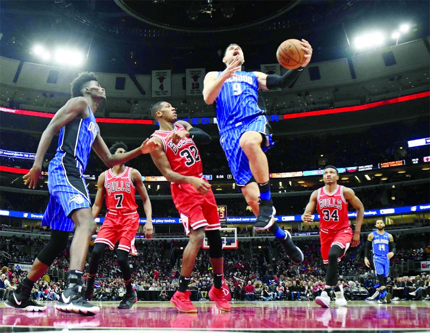 Orlando Magic center Nikola Vucevic (9) goes to the basket as Chicago Bulls guard Kris Dunn (32) defends him during the second half of an NBA basketball game in Chicago on Wednesday. The Magic won 112-84.