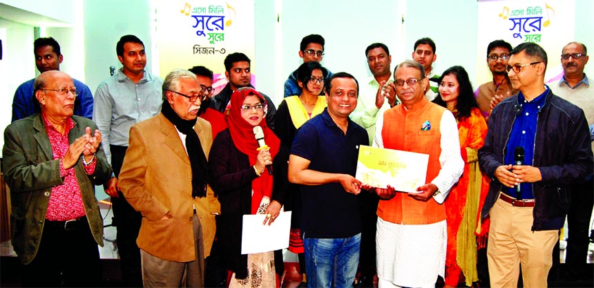 Ali Reza Iftekhar, Managing Director and CEO of EBL handing over the winner's prize to Muhammad Alamgir Hossain of the Bank's Cards Operations, who became champion at the "Esho Mili Surey Surey" music contest, organised by EBL for its employees. Reno