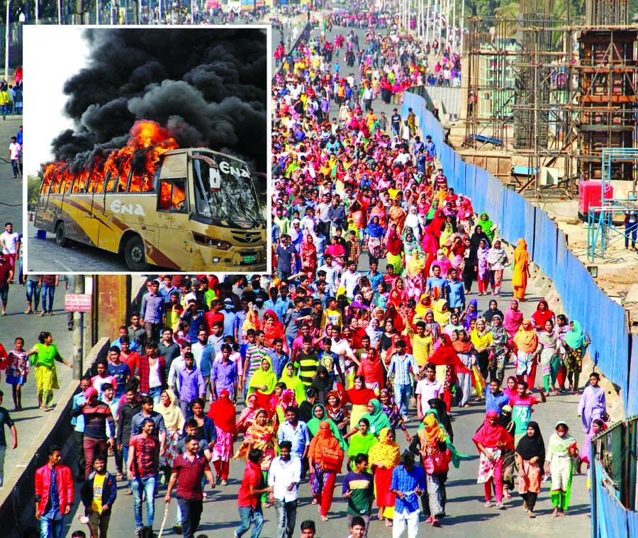 Several hundred agitated garment workers stage demonstration in Uttara blocking the Airport Road for about five hours, demanding implementation of minimum wages in entry level. A bus was torched (inset) by the workers on Monday.