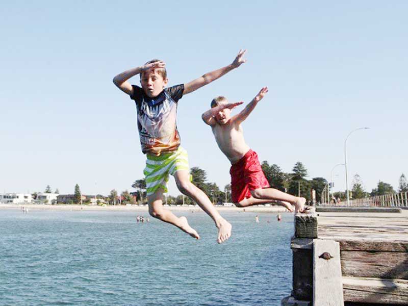 Children jump into the water off Altona pier in Melbourne, Australia.