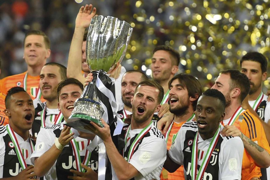 Juventus' Paulo Dybala (center left) and Juventus' Miralem Pjanic raise the trophy at the end of the Italian Super Cup final soccer match between AC Milan and Juventus at King Abdullah stadium in Jeddah, Saudi Arabia on Wednesday.