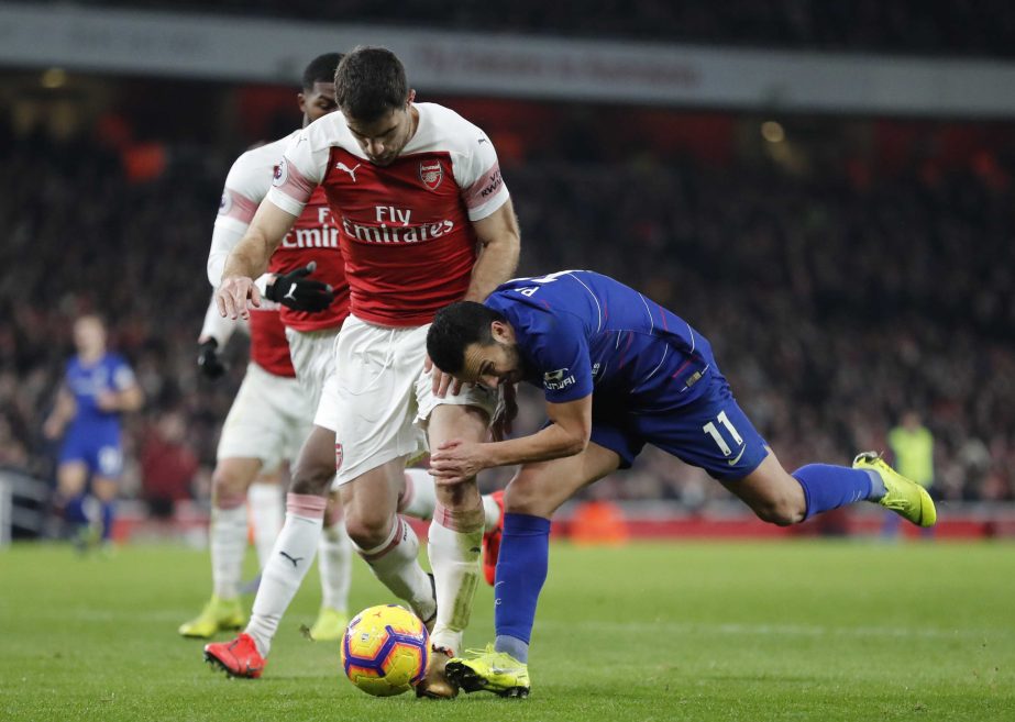 Chelsea's Pedro (right) falls as he vies for the ball with Arsenal's Sokratis Papastathopoulos during the English Premier League soccer match between Arsenal and Chelsea at the Emirates stadium in London on Saturday.