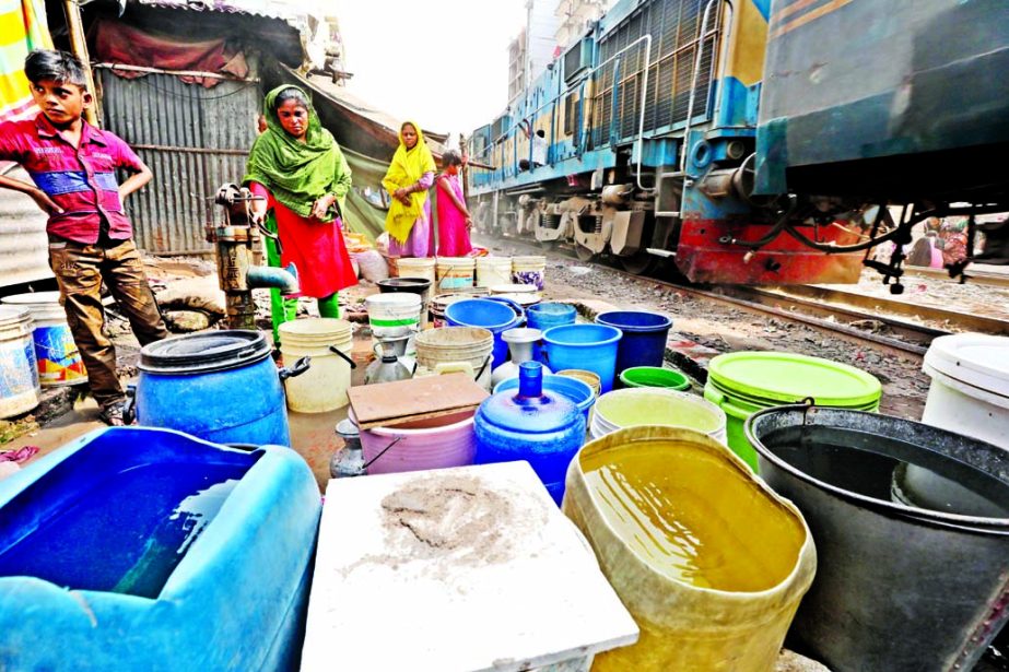 Dwellers of illegal shanties built close to railway line waiting with buckets for fetching waters from WASA pipeline. This photo was taken from Moghbazar area on Saturday.