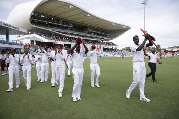 West Indies' captain Jason Holder (right) leads his team out the field after defeating England by 381 runs on day four of the first cricket Test match at the Kensington Oval in Bridgetown, Barbados on Saturday.