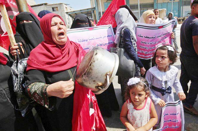 A Palestinian woman drums of a cooking pot during a protest against a US decision to cut funding to the United Nations Relief and Works Agency (UNRWA), outside an aid distribution center, in Khan Yunis in the southern Gaza Strip