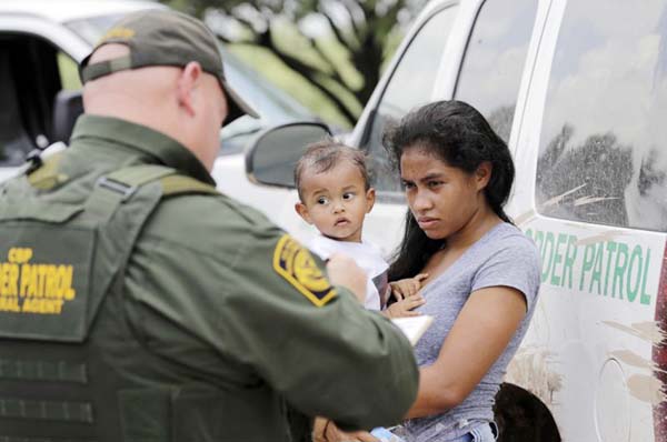A mother migrating from Honduras holds her 1-year-old child as surrendering to US Border Patrol agents after illegally crossing the border near McAllen, Texas.