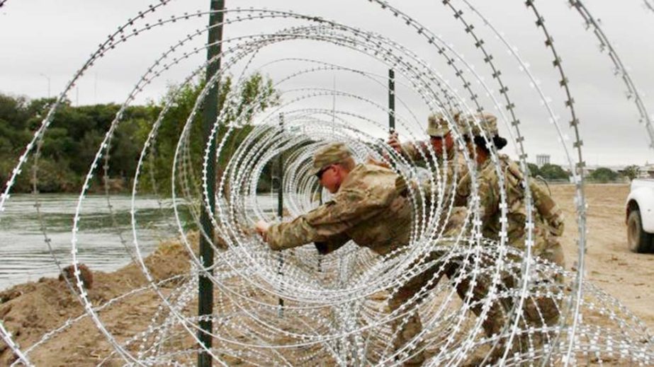 Soldiers are helping to lay miles of razor wire along the US-Mexico border.