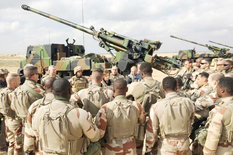 French soldiers from the international coalition against the Islamic State group stand in front of a gun-howitzer near Al-Qaim in Iraq