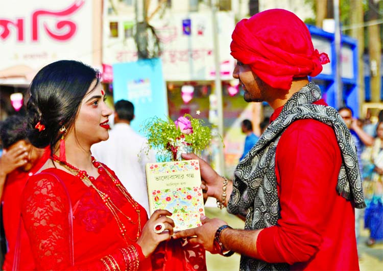 A young lover is seen presenting a book of love stories to her fiancÃ© on the eve of Valentine's Day in exchange of flower on Thursday. This photo was taken from the premises of Bangla Academy Boi Mela.