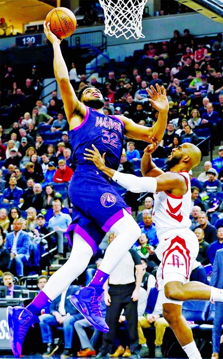 Minnesota Timberwolves' Karl-Anthony Towns (left) goes in for a layup as Houston Rockets' Chris Paul defends in the first half of an NBA basketball game in Minneapolis on Wednesday.