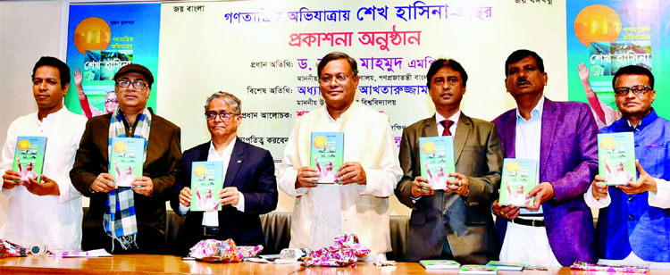 Information Minister Dr. Hasan Mahmud along with other distinguished persons holds the copies of a book titled 'Ganotantrik Avijatrai Sheikh Hasina' written by Sujan Halder at its cover unwrapping ceremony in Poet Sufia Kamal Auditorium of the National