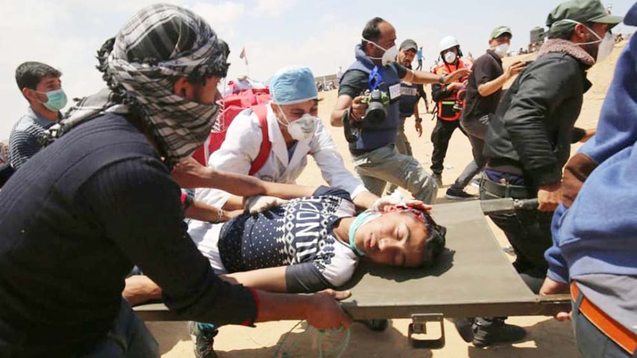 Palestinians carry a protester injured during clashes with Israeli forces along Gaza border