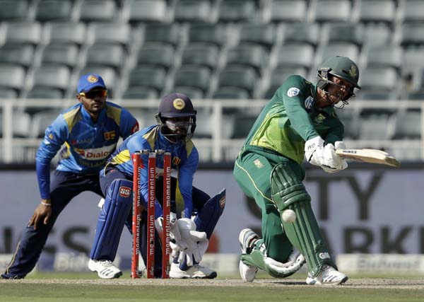 South Africa's batsman Quinton de Kock (right) plays a shot as Sri Lanka's wicketkeeper Niroshan Dickwella (middle) and teammate watch on during the first One Day International cricket match between South Africa and Sri Lanka at the Wanderers stadium in