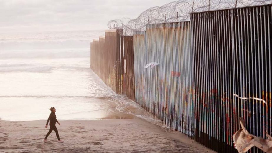 A woman walks on the beach next to the border wall topped with razor wire in Tijuana, Mexico. U.S. President Donald Trump's plan to declare a State of Emergency in order to secure new funding for the wall has hit opposition in the Senate.