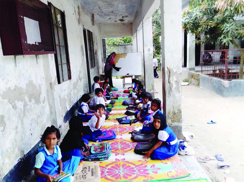 DAMUDYA (Shariatpur): Students of 1 No Damudya Model Govt Primary School attending their classes at the abandon school balcony . This snap was taken yesterday.