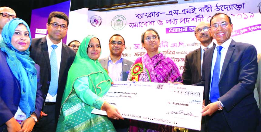 Education Minister Dr. Dipu Moni, handing over a cheque to new women entrepreneur Farida Rahman, Proprietor of MS Shama Bricks on behalf of Shahjalal Islami Bank Limited, at the 'Banker-SME Nari Uddokta Somabesh and Ponno Prodorshony Mela-2019' organiz