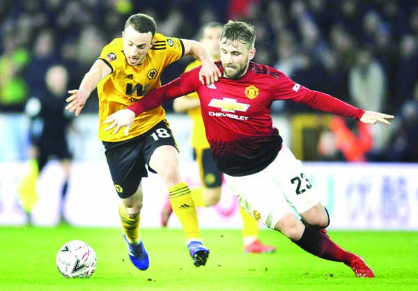 Wolverhampton's Diogo Jota (left) and Manchester United's Luke Shaw challenge for the ball during the English FA Cup Quarter Final soccer match between Wolverhampton Wanderers and Manchester United at the Molineux Stadium in Wolverhampton, England on Sa