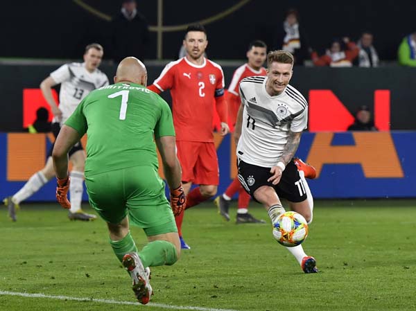 Serbia goalkeeper Marko Dmitrovic (left) makes a save in front of Germany's Marco Reus (right) during a international friendly soccer match between Germany and Serbia at the Volkswagen Arena stadium in Wolfsburg, Germany on Wednesday.