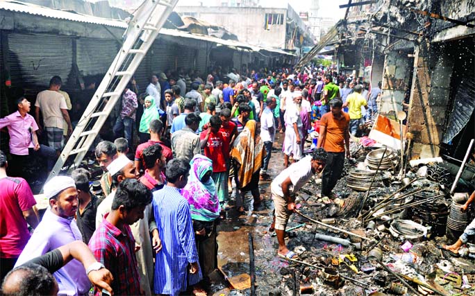 Traders searching to locate their damaged goods after the fire was doused by the fire-fighters at DNCC kitchen market in Gulshan on Saturday.
