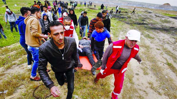 Medics and protester evacuate a wounded youth, who was shot by Israeli troops from near the fence of the Gaza Strip's border with Israel, while marking first anniversary of Gaza border protests east of Gaza City.