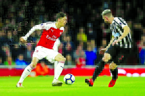 Arsenal's Mesut Ozil (left) competes for the ball with Newcastle's Paul Dummett during the English Premier League soccer match between Arsenal and Newcastle United at Emirates stadium in London on Monday.