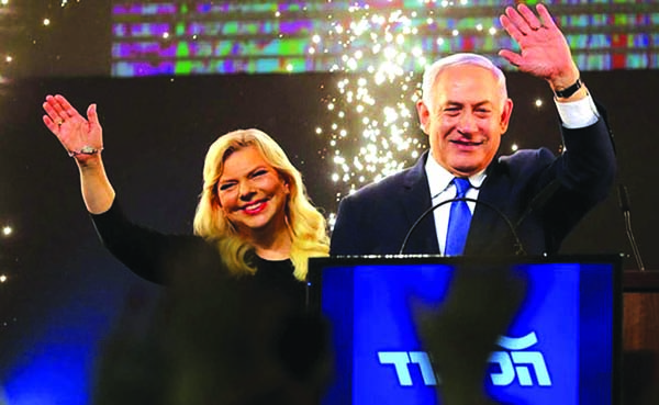 Israeli Prime Minister Benjamin Netanyahu and his wife Sara react as they stand on stage following the announcement of exit polls at the party headquarters in Tel Aviv on Wednesday.