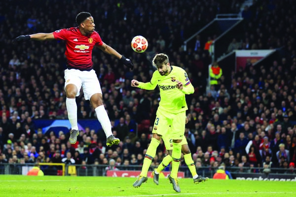 Manchester United's Anthony Martial (left) and Barcelona's Gerard Pique jump for the ball during the Champions League quarterfinal, first leg, soccer match between Manchester United and FC Barcelona at Old Trafford stadium in Manchester, England on Wedn