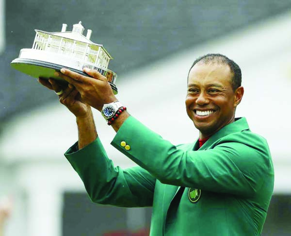 Tiger Woods wears his green jacket holding the winning trophy after the final round for the Masters Golf tournament in Augusta, Ga on Sunday.