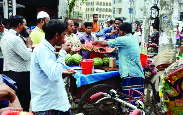 Pedestrians are taking taste of watermelon in the open air in city's Gulistan area, which unhygienic and harmful to health. This photo was taken on Thursday.