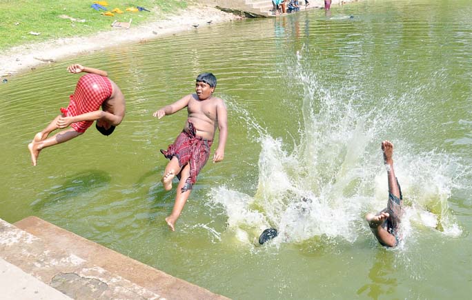 Life has turned miserable due to excessive heat in Chattogram city . Children are seen taking bath in a pond yesterday .