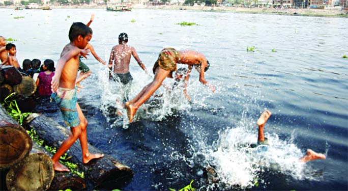 Children jump into the stinky water of the Buriganga River during a hot-summer day taking risk of life. The photo was taken from riverbank at Kamrangirchar in Dhaka on Friday.