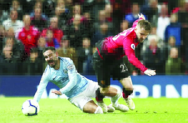 Manchester City's Ilkay Gundogan (left) fights for the ball with Manchester United's Luke Shaw during the English Premier League soccer match between Manchester United and Manchester City at Old Trafford Stadium in Manchester, England on Wednes