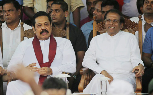 Sri Lankan President Maithripala Sirisena, right, and his newly appointed prime minister Mahinda Rajapaksa, center attend a rally held outside the parliamentary complex as a police officer tries to control the crowd in Colombo