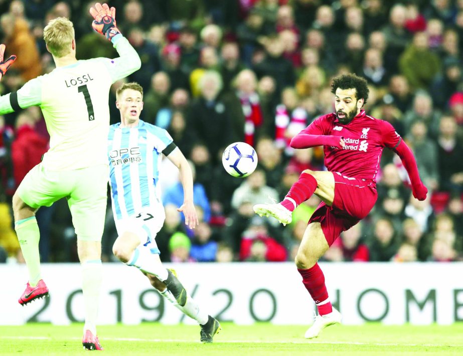 Liverpool's Mohamed Salah (right) kicks the ball to score his side's third goal during the English Premier League soccer match between Liverpool and Huddersfield Town at Anfield Stadium, in Liverpool, England on Friday.