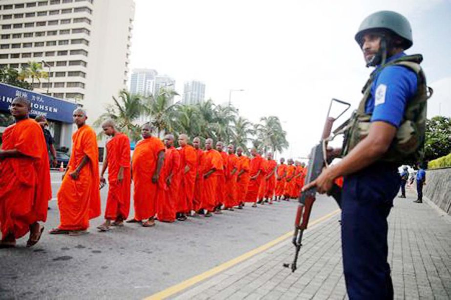 Security personnel stand guard as monks take part in a Buddhist ceremony as a tribute to victims, a week after a string of suicide bomb attacks across the island on Easter Sunday, at Kingsbury Hotel in Colombo, Sri Lanka on Sunday.