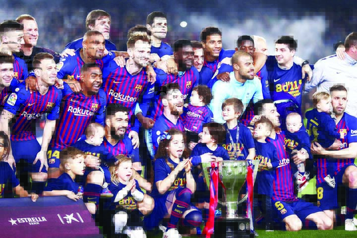 FC Barcelona players, with their children, pose with their trophy after winning the Spanish League title, at the end of the Spanish La Liga soccer match between FC Barcelona and Levante at the Camp Nou stadium in Barcelona, Spain on Saturday. Barcelona cl