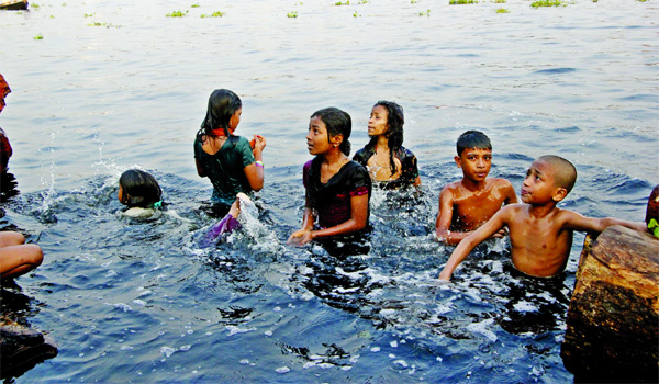 To heave a sigh of relieve, boys and girls taking bath in stinky water of Buriganga River as sweltering heat continues. This photo was taken from city's Hasnabad area on Sunday.