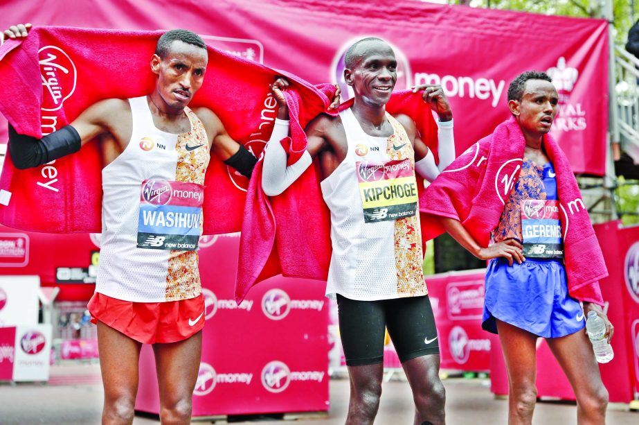 First place winner Kenya's Eliud Kipchoge (center) poses with second place winner Ethiopia's Mosinet Geremew (right) and third place winner Ethiopia's Mule Wasihun in the men's race at the 39th London Marathon in London on Sunday.