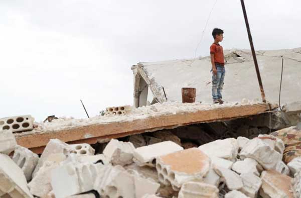 A Syrian boy stands above the rubble of a building in the village of Rabaa Jour in the the jihadi-held Syrian province of Idlib on Monday following reported shelling and airstrikes in the area.