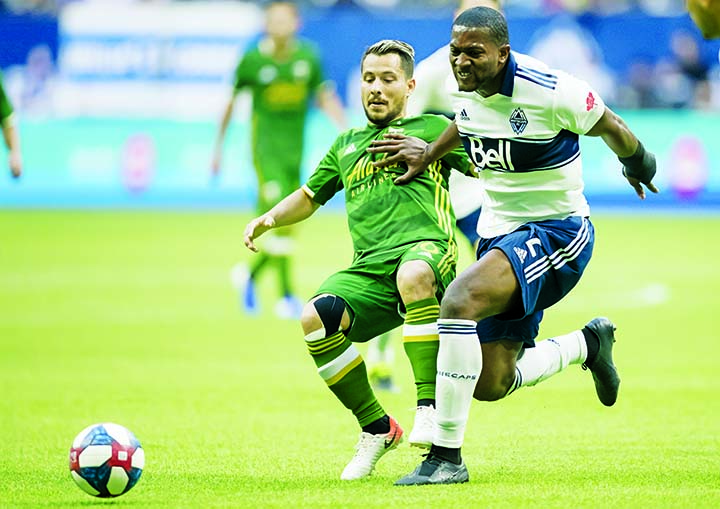 Vancouver Whitecaps' Doneil Henry (front right) and Portland Timbers' Sebastian Blanco vie for the ball during the first half of an MLS soccer match in Vancouver, British Columbia on Friday.