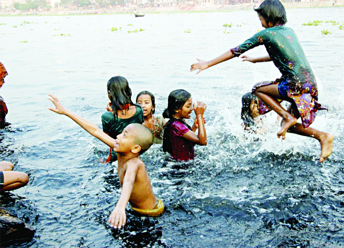Minors jumping and bathing at the rotten waters of Buriganga River to get rid of excessive heat of the scorching sun taking risk of life. This photo was taken from Sadarghat area on Saturday.
