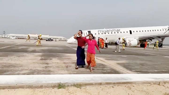 Passengers walk away from the plane after Myanmar National Airlines flight UB103 landed without a front wheel at Mandalay International Airport in Tada-u, Myanmar.