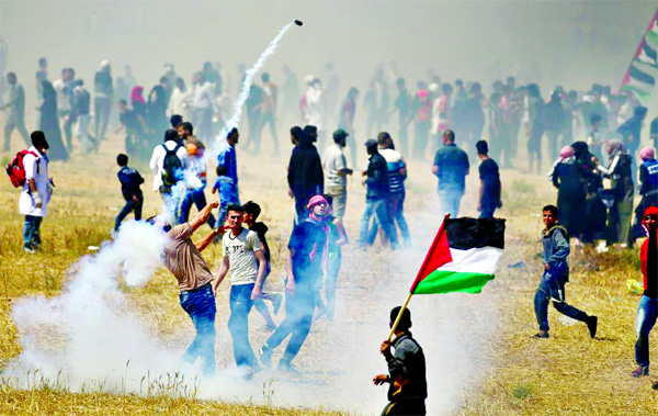 A Palestinian demonstrator hurls back a tear gas canister fired by Israeli forces during a protest marking the 71st anniversary of the 'Nakba', or catastrophe, when hundreds of thousands fled or were forced from their homes in the war surrounding Israel