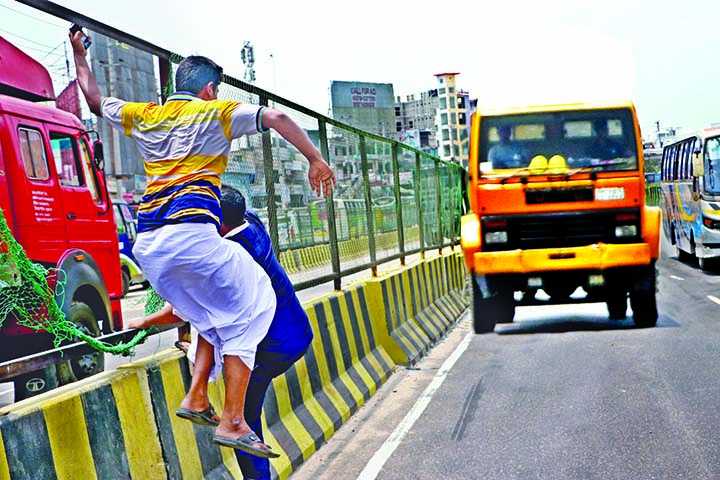 Two pedestrians tear of the iron net on the road divider on Dhaka-Chattogram Highway at Sonargaon Chowrasta area just to cross on the side of the busy road risking their lives on Wednesday.