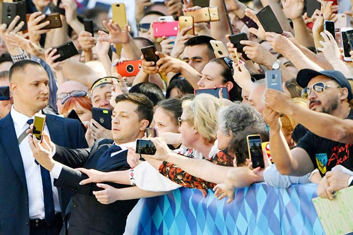 In a sign of his more informal style, Zelensky exchanged high fives with supporters waiting outside and took selfies with them