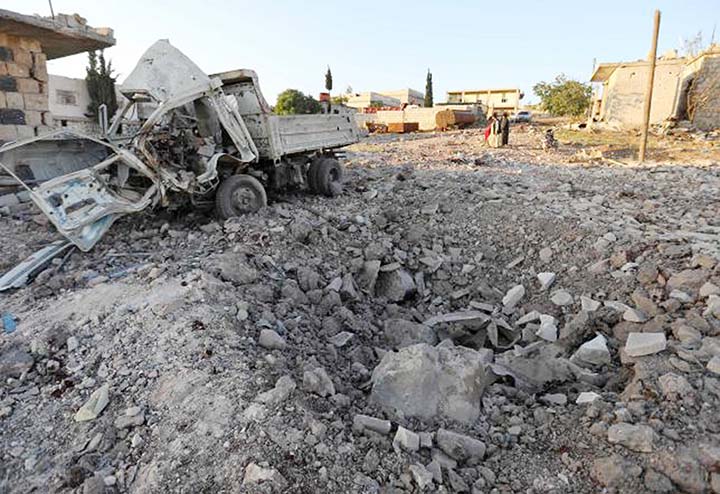 A damaged vehicle lies next to a crater cased by reported airstrikes by the Syrian regime ally Russia, in the town of Kafranbel in the rebel-held part of the Syrian Idlib province on 20 May.