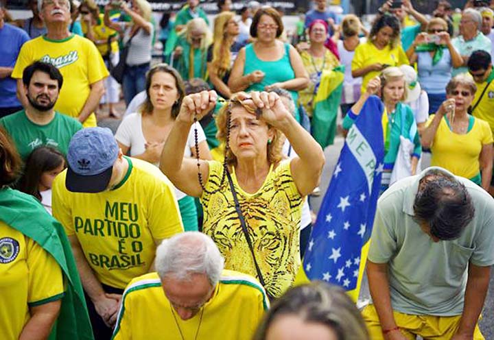 A supporter of Brazilian President Jair Bolsonaro prays as she takes part in a demonstration to shore up the ultraconservative government as it faces growing opposition, in Rio de Janeiro, while marches are planned across Brazil.